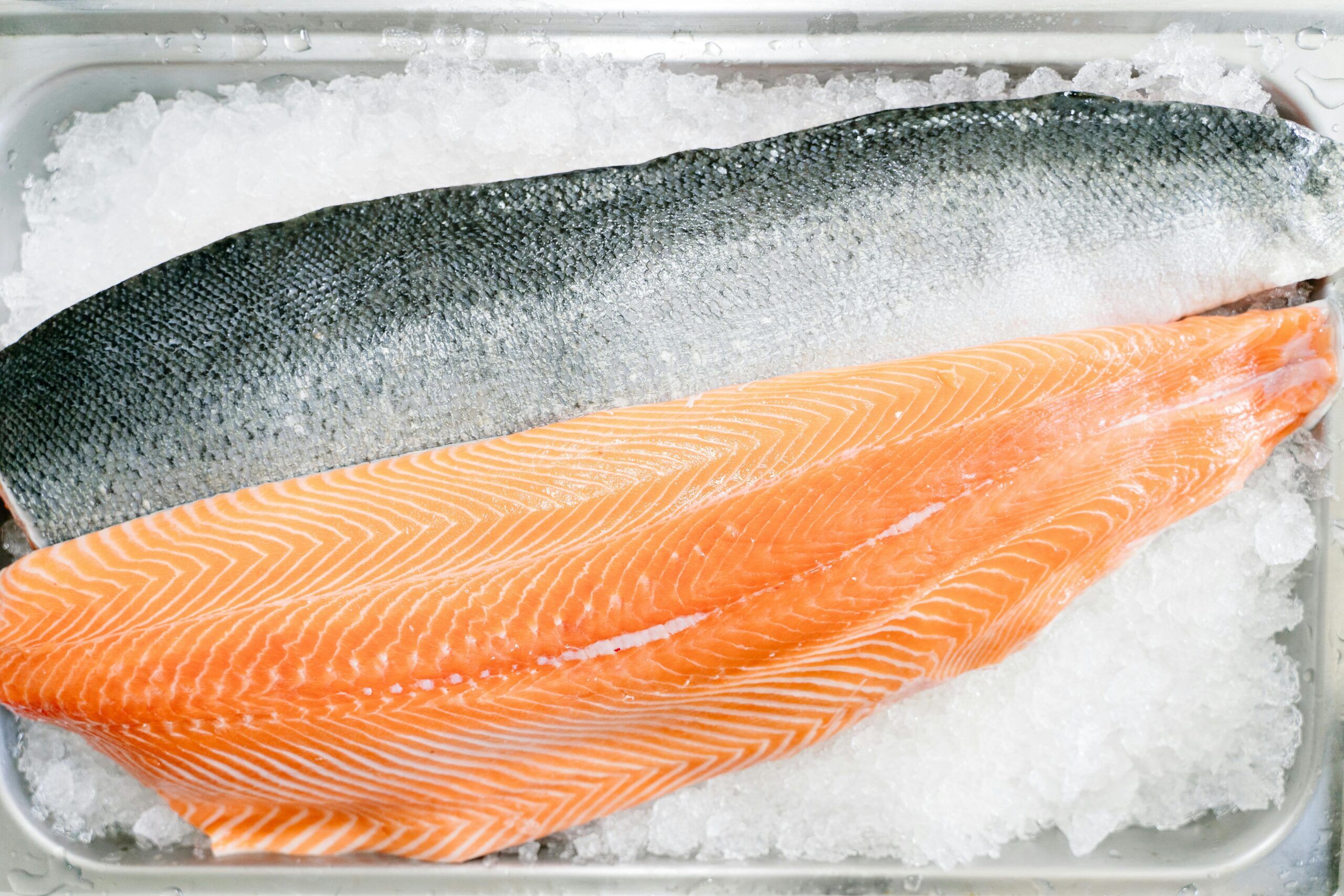 Close-up of a raw salmon fillet on ice, showcasing its fresh and high-quality texture.